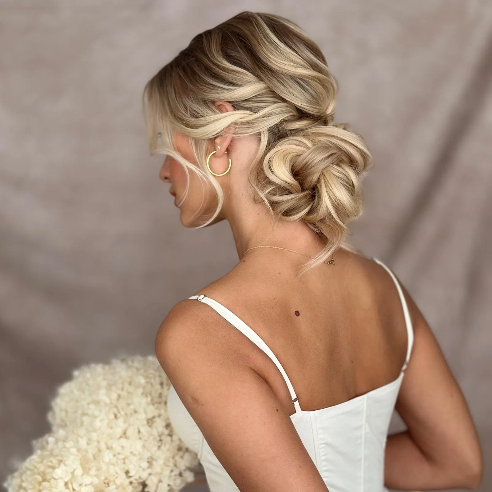 Bridal Hair von Kasia Fortuna: lockerer, tief sitzender Dutt in Blond mit weichen Wellen und gesichtsumrahmenden Strähnen
