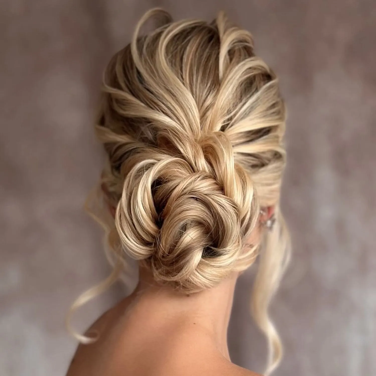 Bridal Hair von Kasia Fortuna: verspielter, tief sitzender Knoten in Blond mit lockeren, gewellten Strähnen, Rückansicht