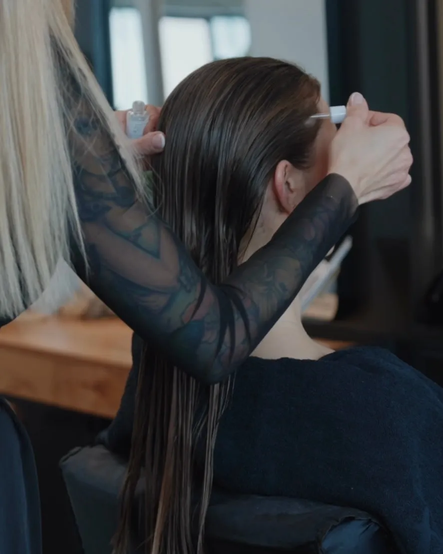 Kopfhautpflege: Jasmin Werner trägt mit einer Pipette ein Serum auf die Kopfhaut eines Models auf