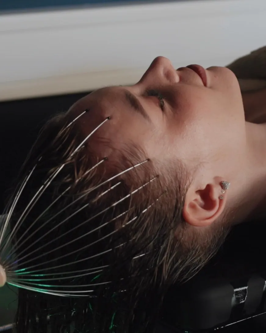 Kopfmassage mit einem Massagewerkzeug: Ein Model liegt entspannt mit geschlossenen Augen am Head-Spa-Becken