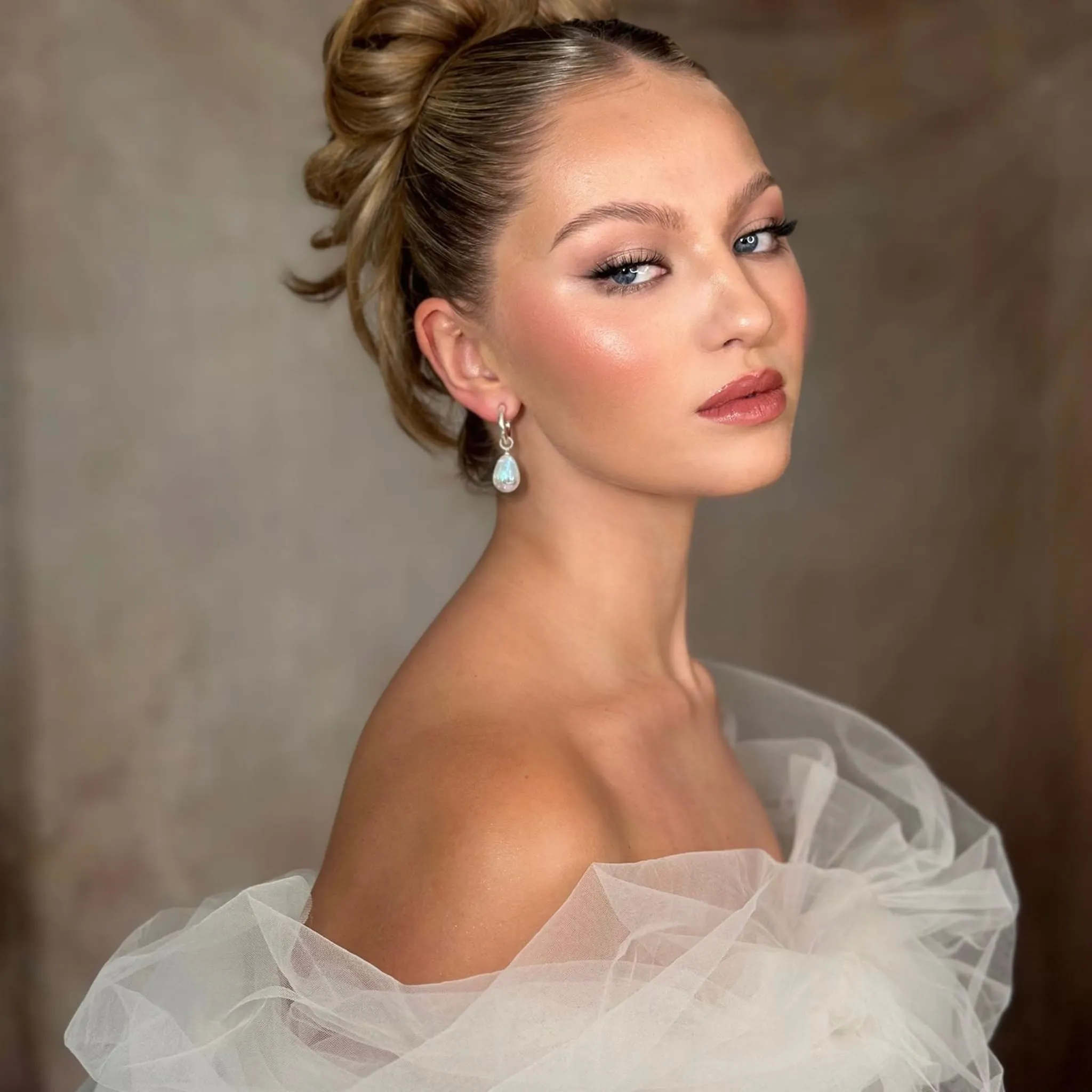 Bridal Make-up von Kristina Gasperas: strahlender Teint und roséfarbene Lippen, hoher Dutt, Schultern in Tüll