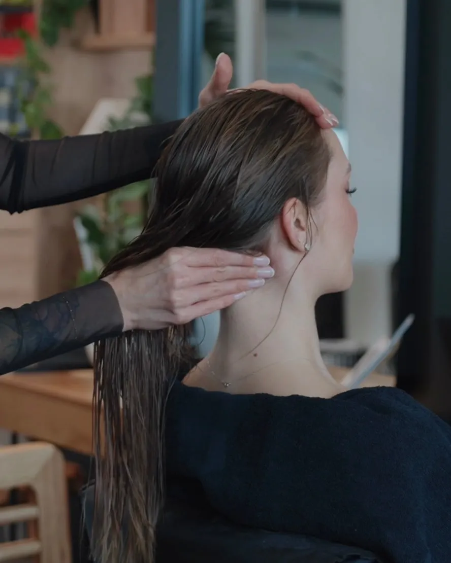 Friseurmeisterin Jasmin Werner massiert Nacken und Kopf eines Models mit nassem Haar