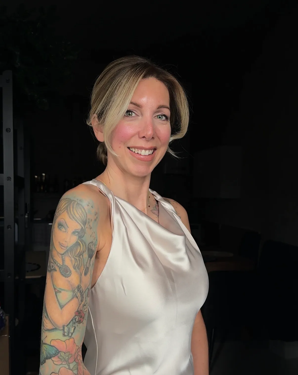 Friseurmeisterin Jasmin Werner lächelnd mit eleganter Hochsteckfrisur und Satin-Top