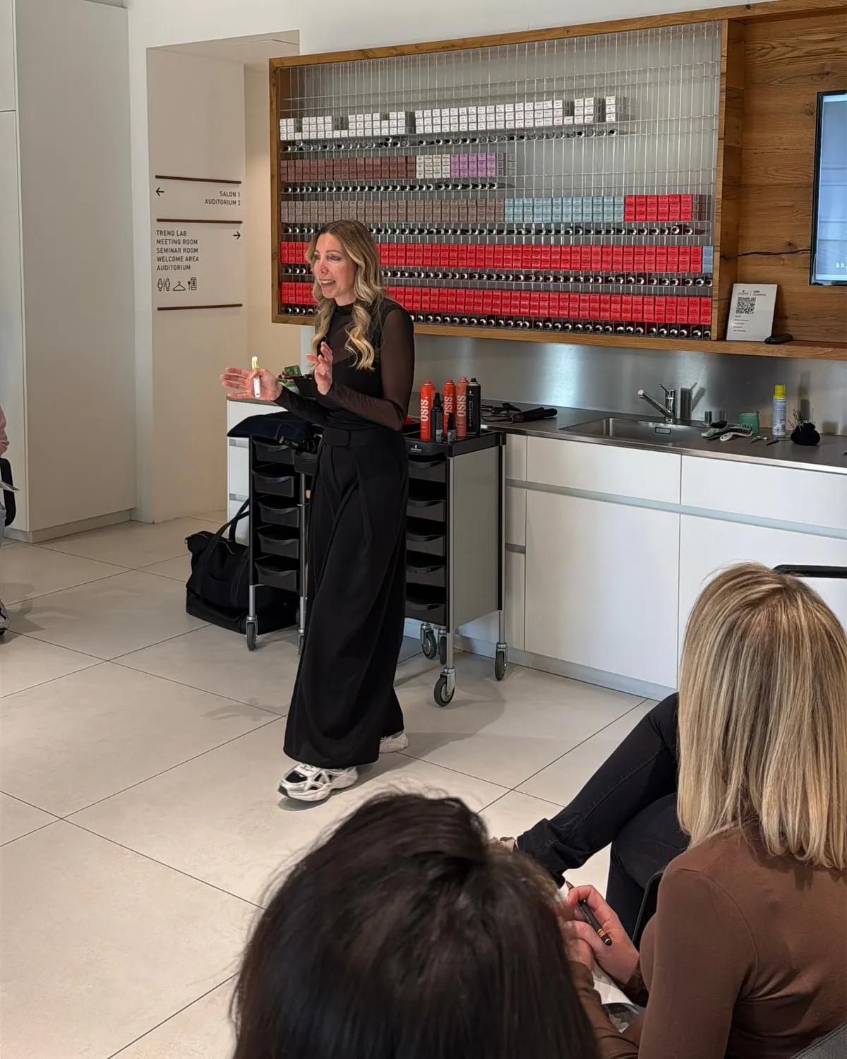 Friseurmeisterin Jasmin Werner spricht in einem Seminar vor einer Gruppe von Teilnehmer:innen