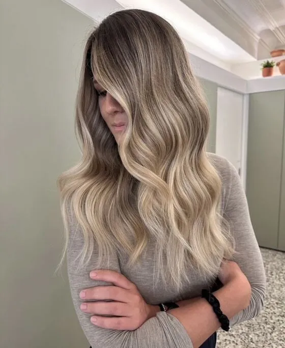 Aschblondes Balayage mit dunklerem Ansatz und weichen Wellen