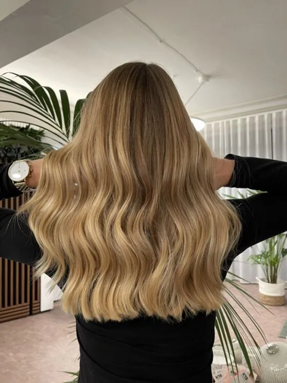 Rückansicht: goldblondes Balayage mit weichen Wellen