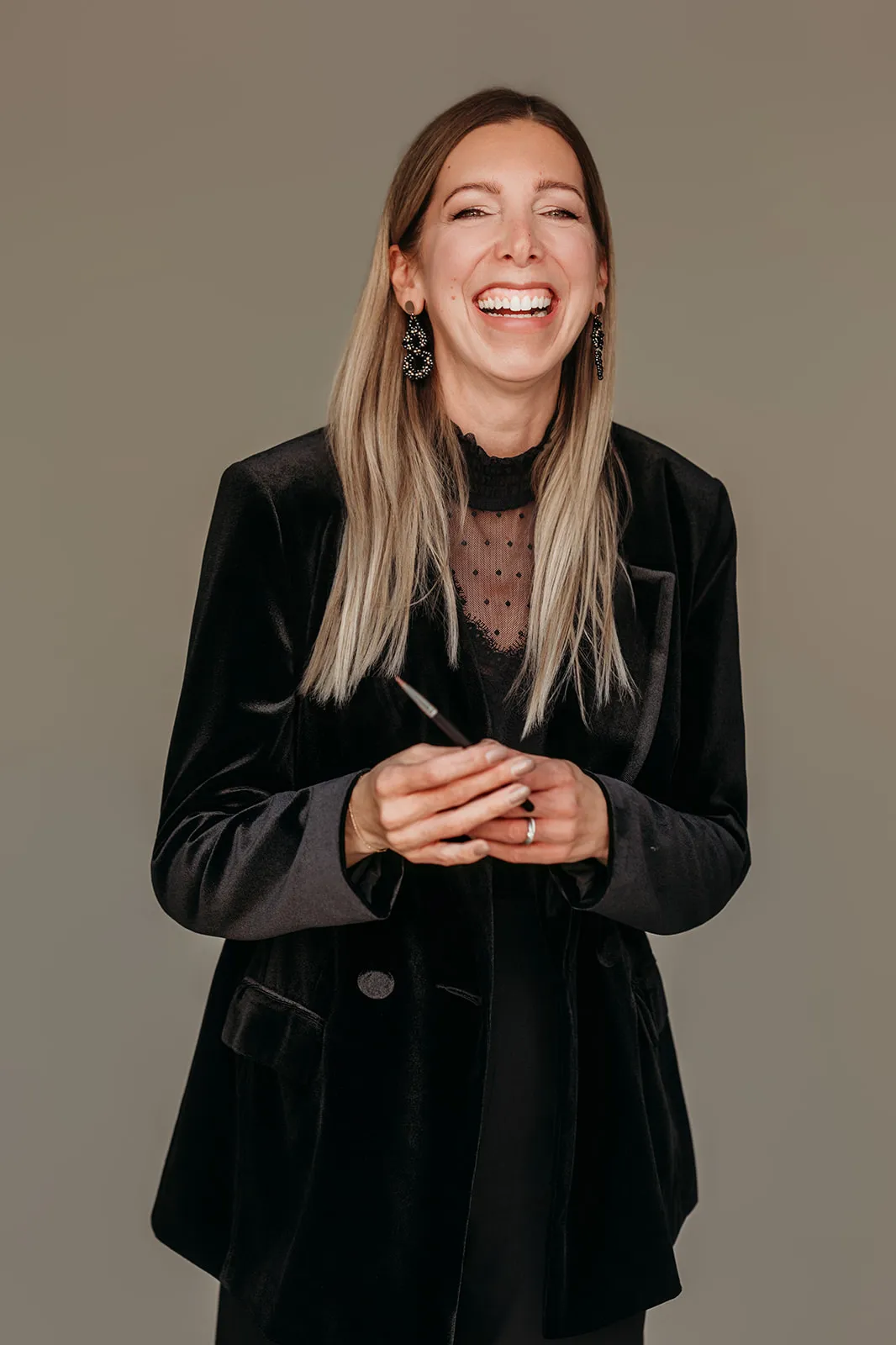 Jasmin Werner lacht herzlich, im schwarzen Samtblazer mit einem Pinsel in der Hand
